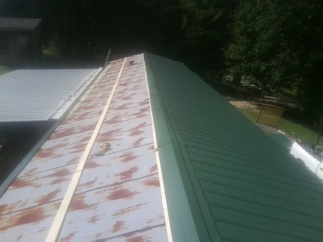 Old rusted panels beside newly installed green metal roofing — Wind Damage Roof Repair by Roofing Brothers in Etna