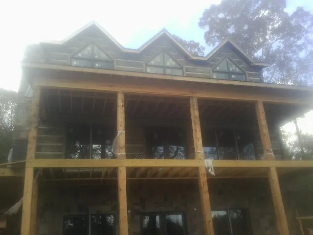 Dormers and porch framing on a large log home under construction — Roof Coating work by our crew in Etna